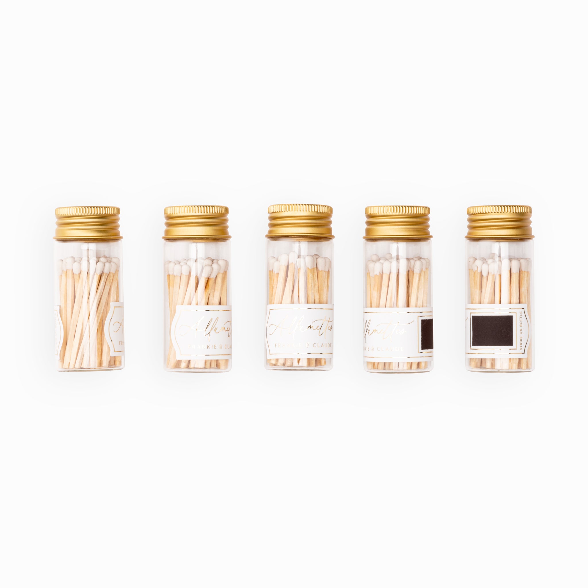 Lineup of Frankie & Claude Allumette Match Jars displaying the classic white match tip color in sleek glass jars with stylish gold lids.