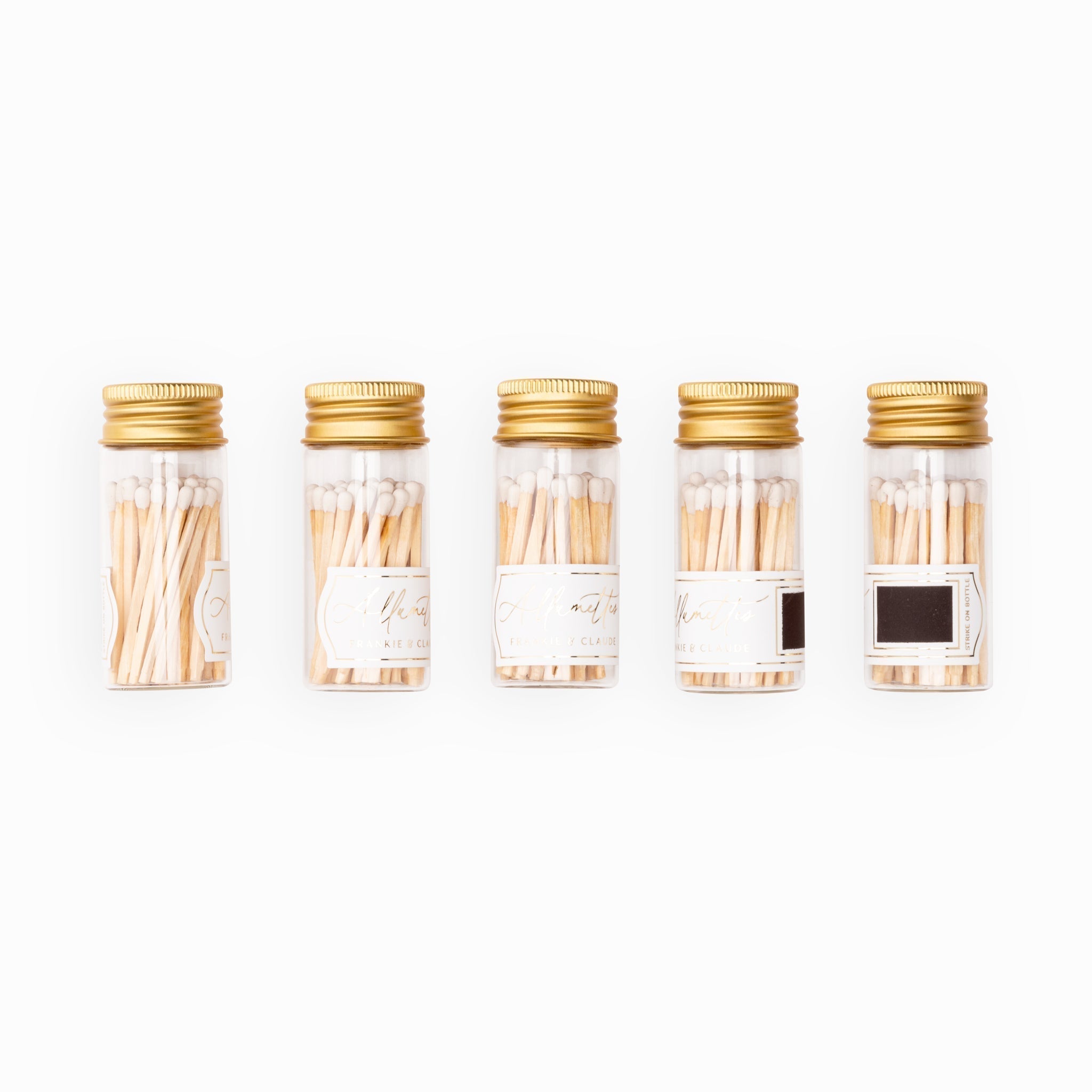 Lineup of Frankie & Claude Allumette Match Jars displaying the classic white match tip color in sleek glass jars with stylish gold lids.