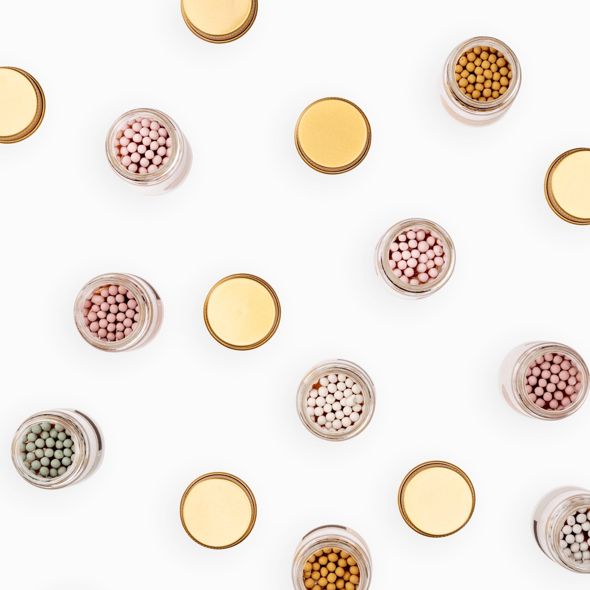 Top-down view of Frankie & Claude Allumette Match Jars with lids, showing match tips in multiple colors including pink, white, and honey gold, arranged in a scattered organic pattern.