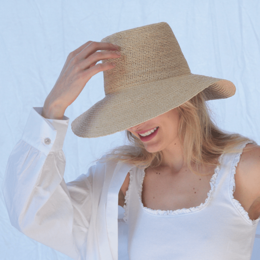 Woman wearing a straw hat against a light blue background