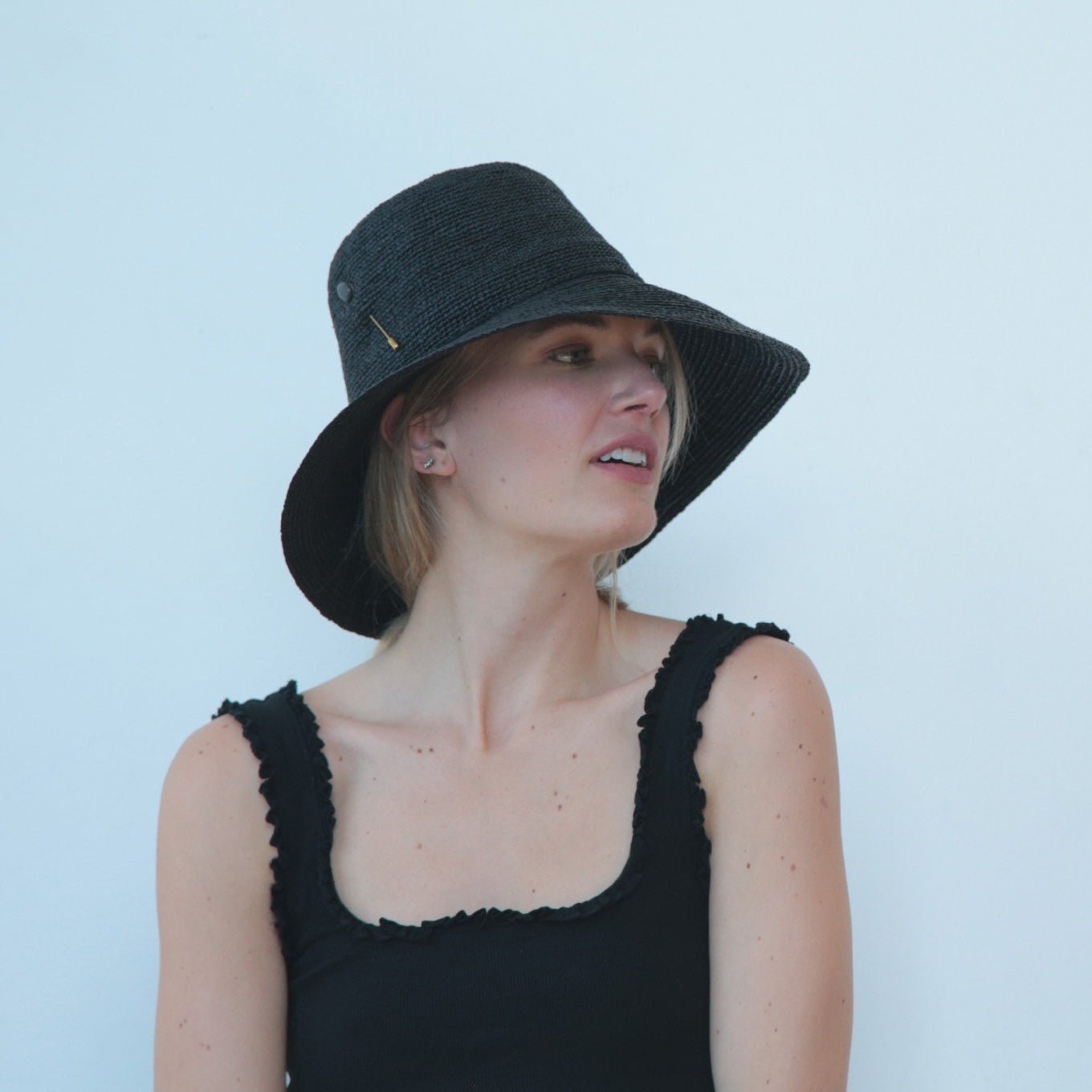Woman wearing a black bucket hat against a light blue background