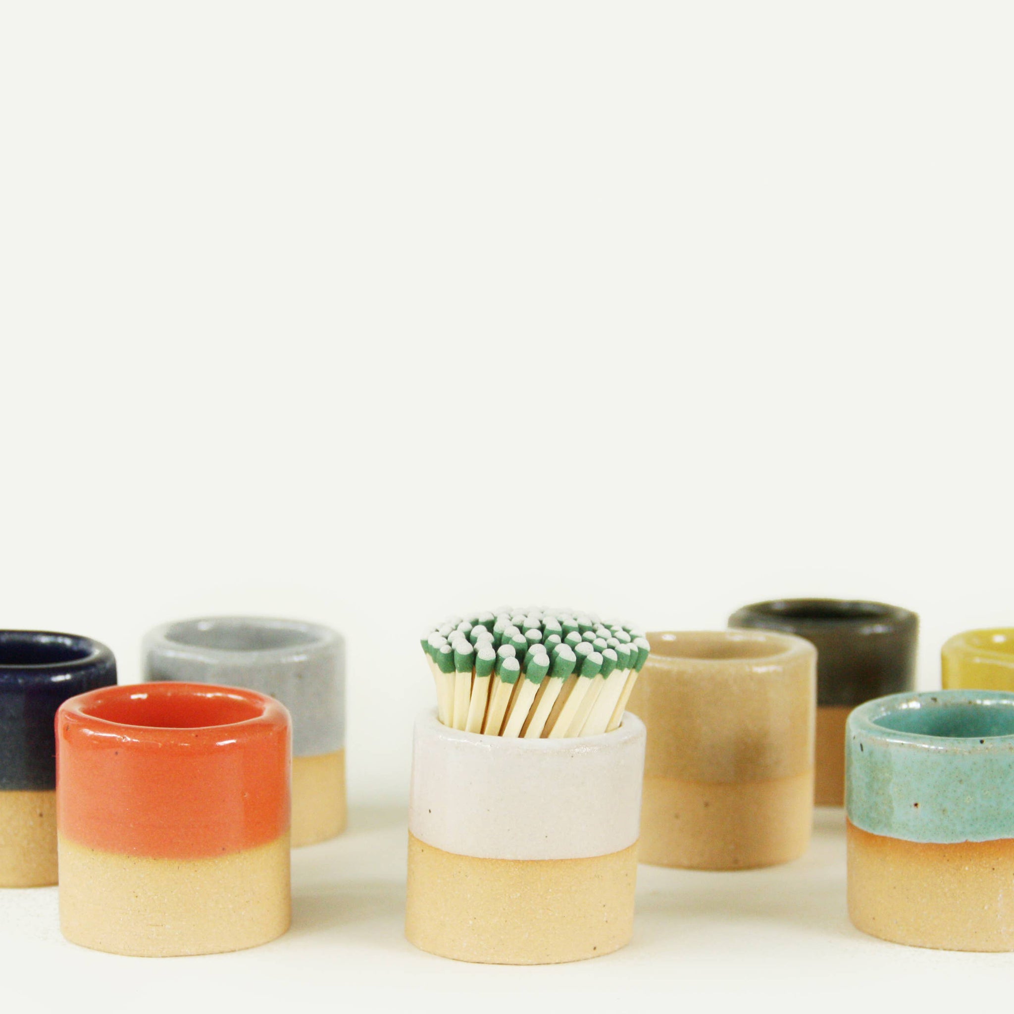 Multiple ceramic match strikers in various colors, with one prominently featuring the white ceramic match striker.