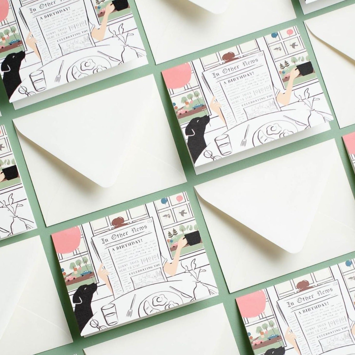 Illustrated chic birthday card on warm white premium cardstock, featuring a woman reading a newspaper at a brunch table with a black lab holding a pink balloon, and a scenic backdrop of birds with balloons through a window.