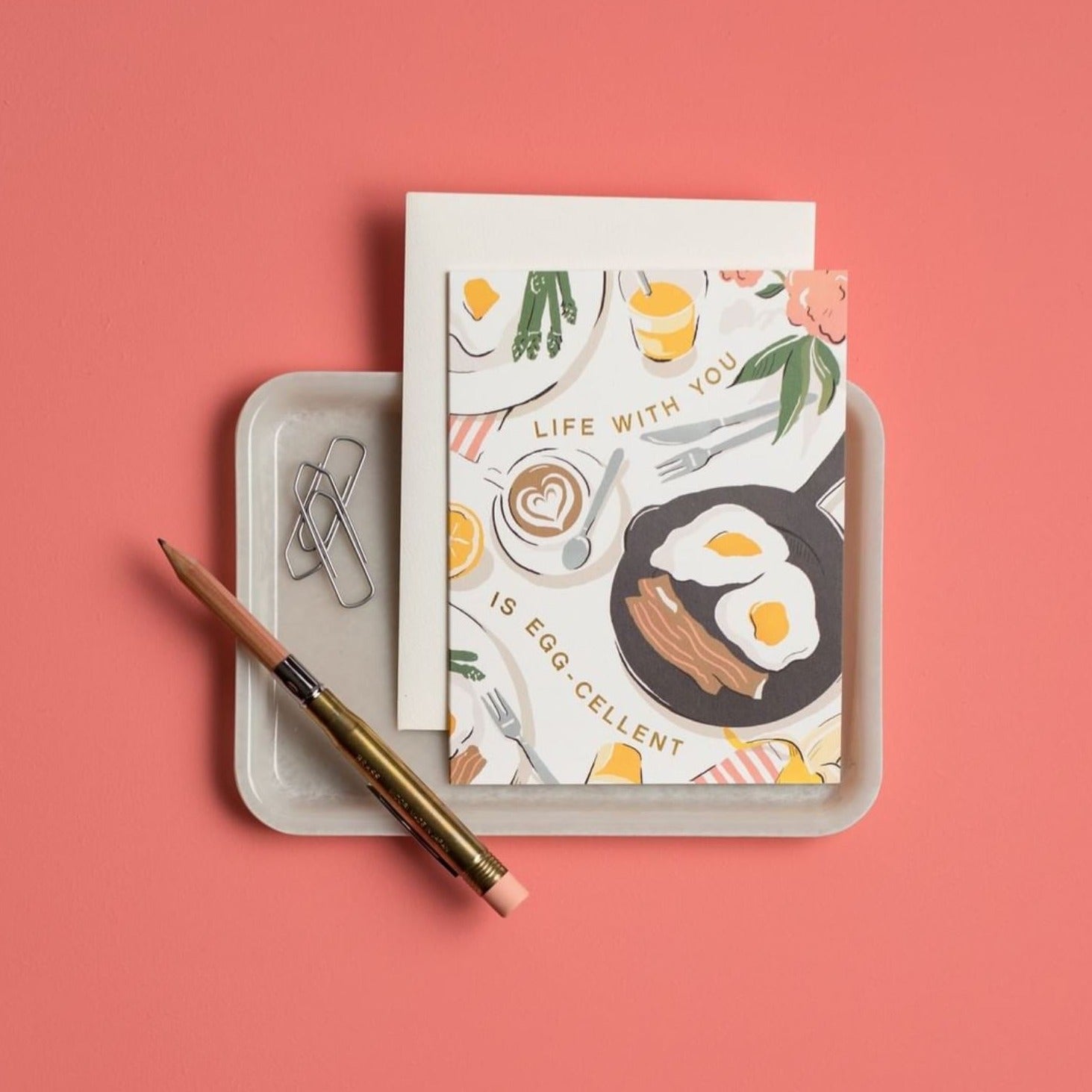 Illustrated 'Just Because' card on warm white premium cardstock, featuring a breakfast tablescape of eggs, bacon, and a latte with the text 'Life With You Is Egg-cellent.