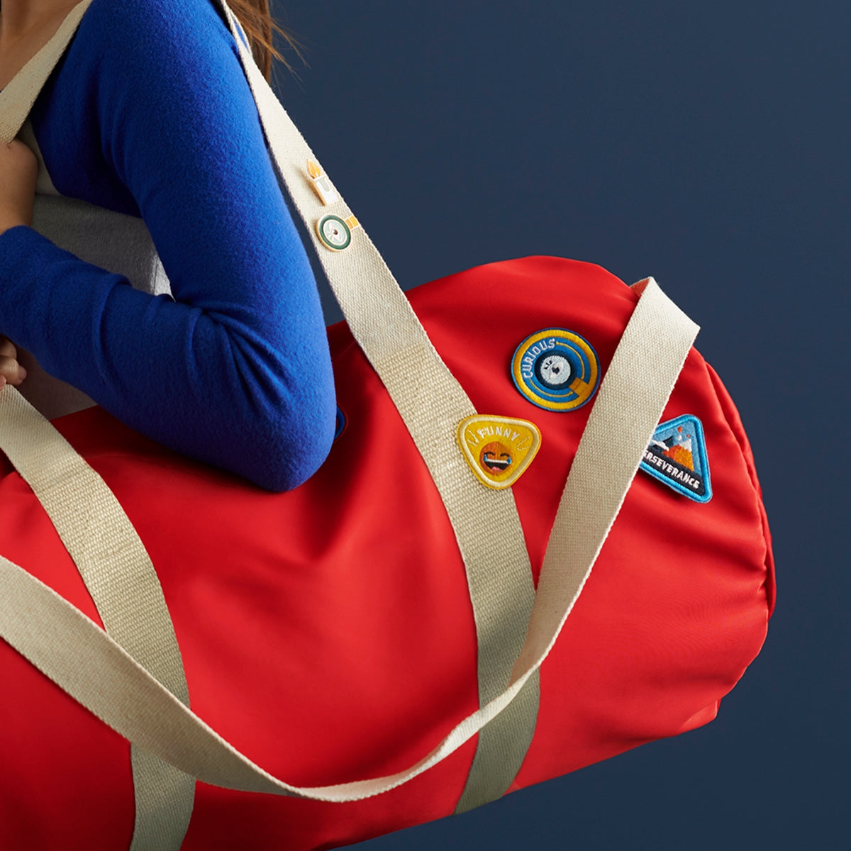 Set of 4 children's character badge patches featuring the traits Kind, Spiritual, Love, and Grateful, with adhesive and iron-on backing, shown on an red duffle bag set against a dark blue background, perfect for customizing backpacks and clothing.