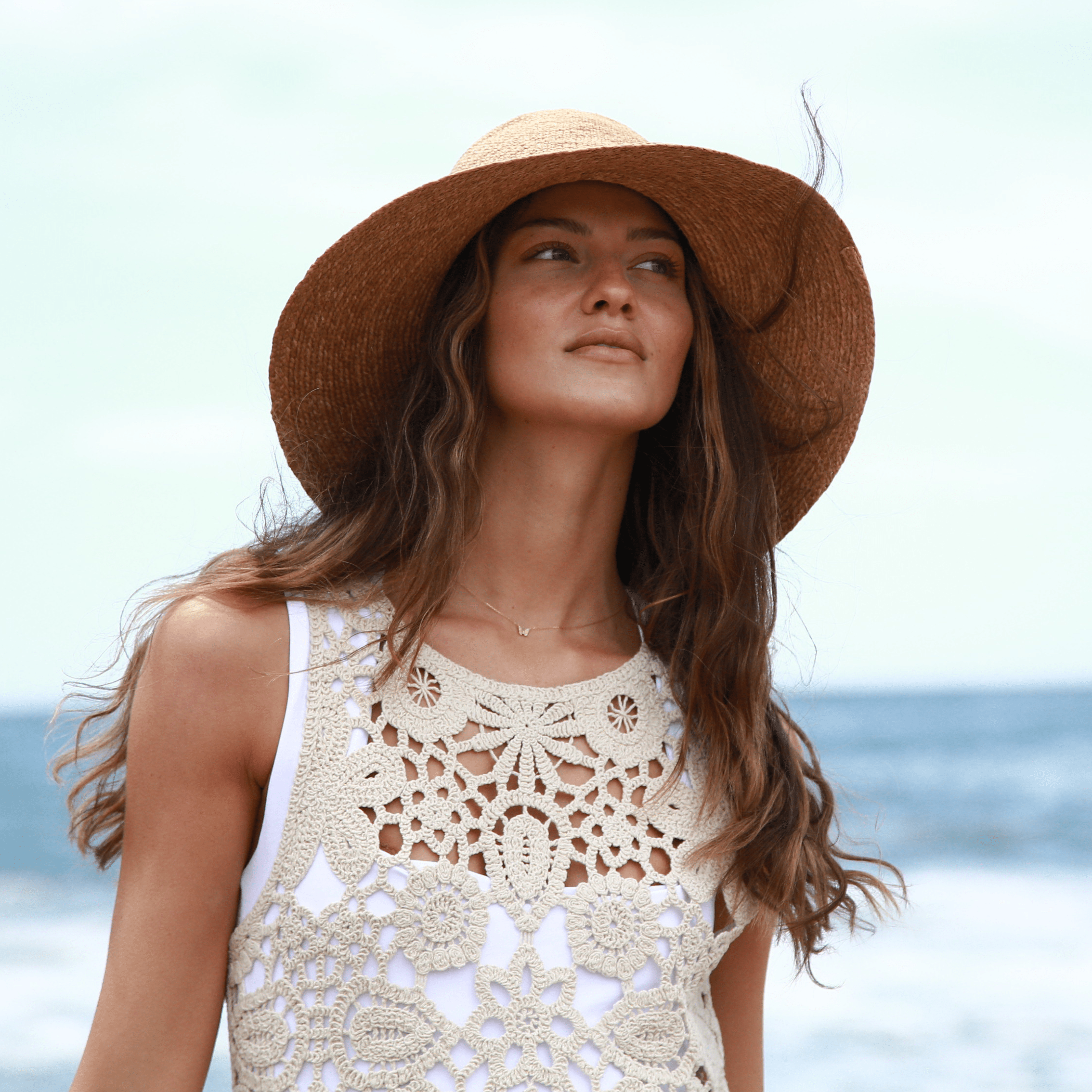 Woman wearing a straw hat and crochet top on a beach