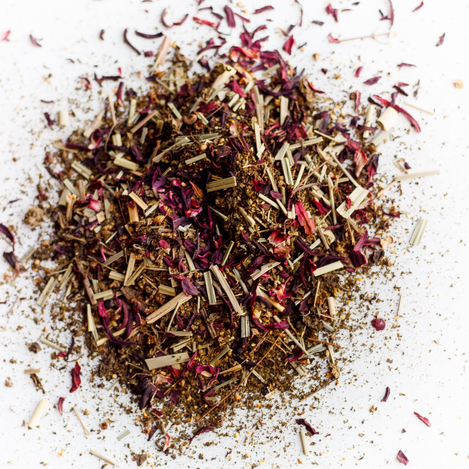 "A pile of loose leaf Blushing Tea, a naturally caffeine-free blend featuring hibiscus, lemongrass, and tulsi. Ideal for a vitamin C boost and creating a vibrant pink brew that's tart, sweet, and citrusy. Perfect for kids and adults alike.