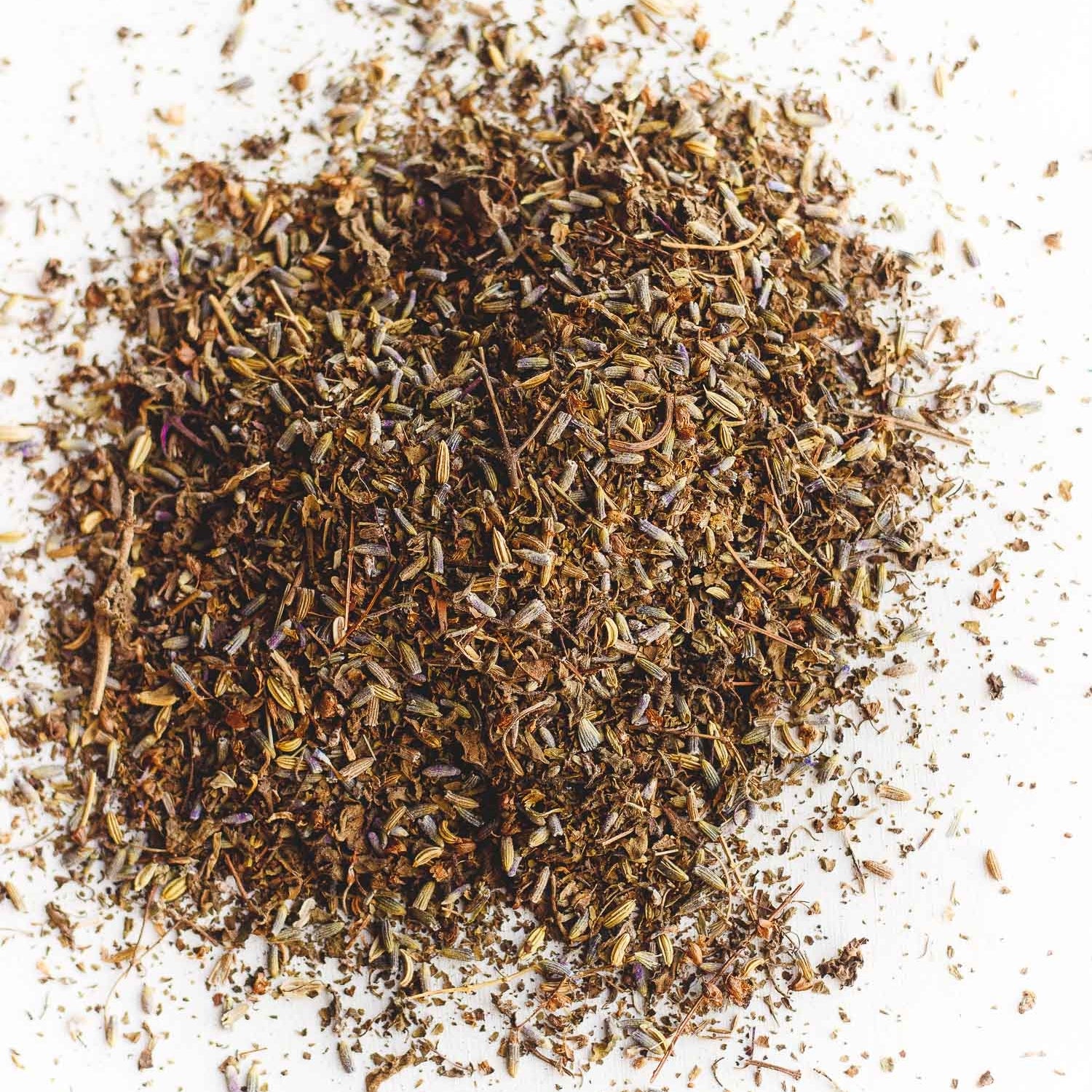 A pile of loose leaf Calm Yo' Tummy Tea, an organic blend featuring tulsi, lavender, fennel seed, and brahmi. Designed to stimulate digestion, soothe upset stomachs, relieve stress, and support lactation. Offers a balanced sweet and savory flavor profile.