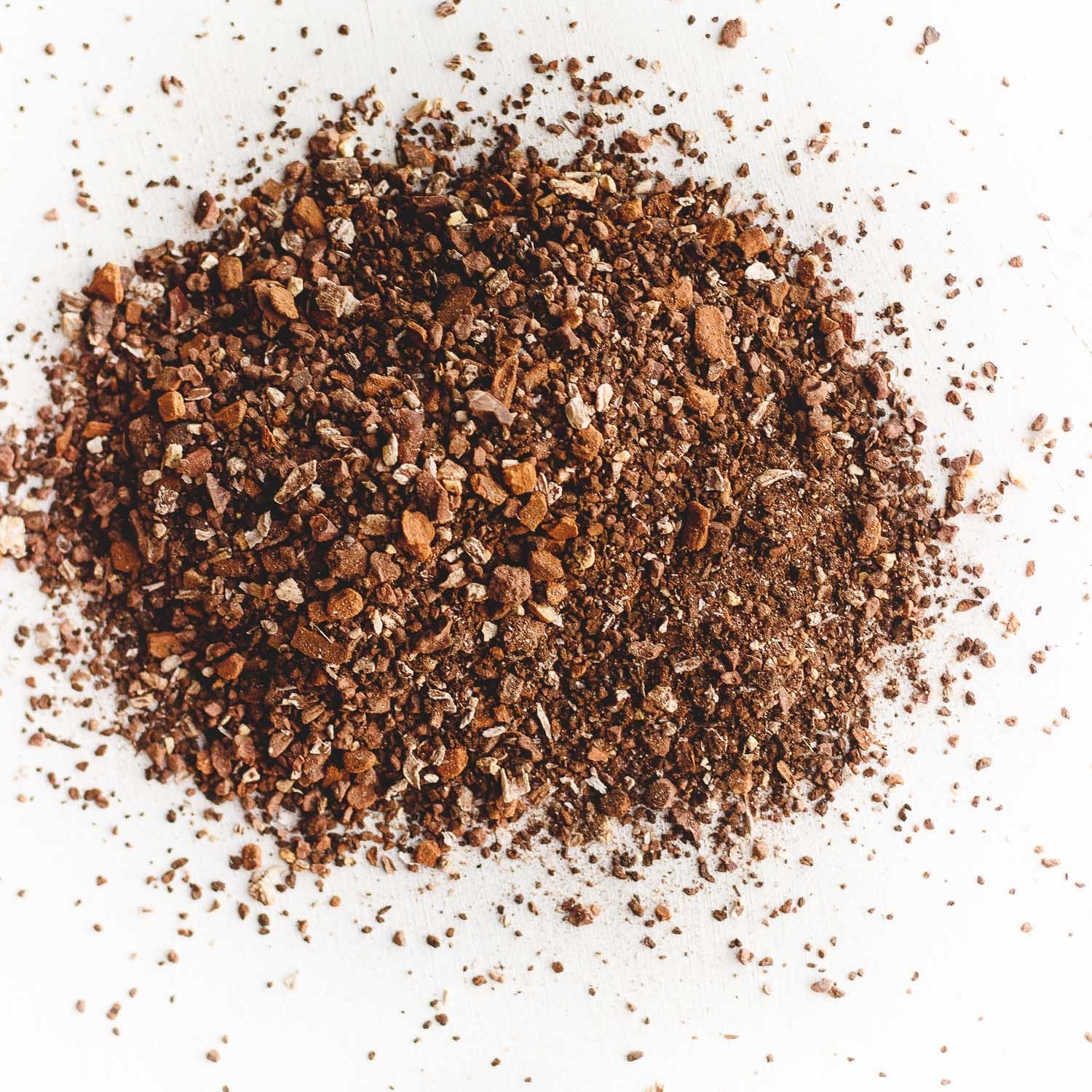 A pile of loose leaf Fake Coffee tea, an organic, energizing blend of cacao, roasted chicory, dandelion root, and sweet cinnamon. Touted as 'life-changing' by BuzzFeed, this tea mimics the feel of coffee while offering a chocolaty, herbaceous flavor and natural energy boost.