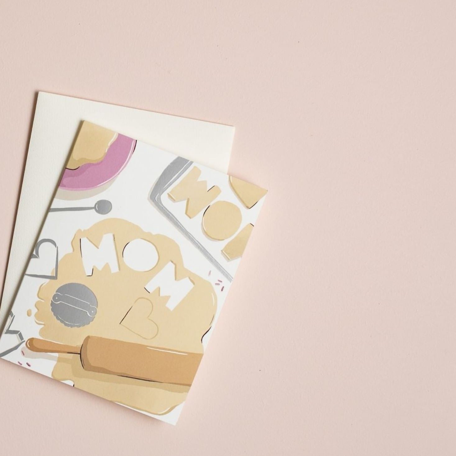 Illustrated Mother's Day card on warm white premium cardstock, featuring rolled-out cookie dough with the word 'Mom' cut out, symbolizing the sweetness and love of a mother's special touch.