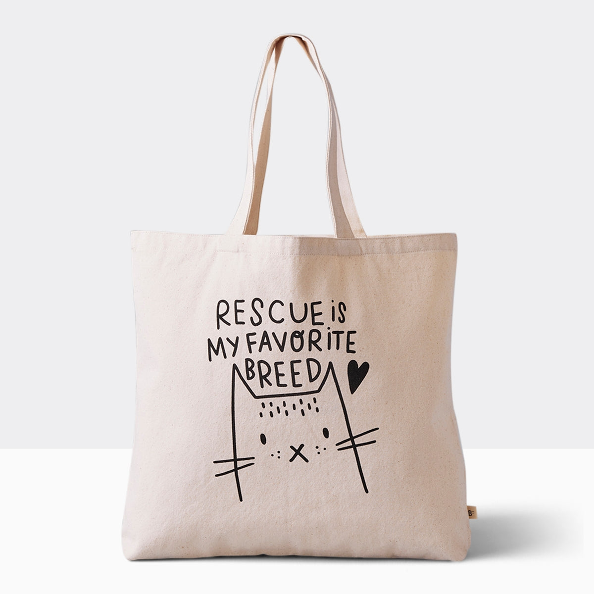 Spacious cotton canvas tote bag featuring a heartwarming cat illustration and the message 'Rescue is my favorite breed,' perfect for eco-conscious pet lovers. Bag is 17.5" wide and 15.5" tall with 10" drop handles, sitting on a plain white urface.