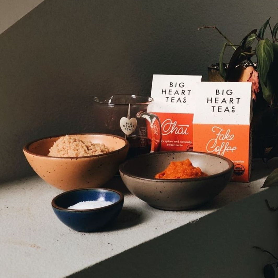 Orange box of Fake Coffee tea on a counter, an organic, energizing blend of cacao, roasted chicory, dandelion root, and sweet cinnamon. Touted as 'life-changing' by BuzzFeed, this tea mimics the feel of coffee while offering a chocolaty, herbaceous flavor and natural energy boost.