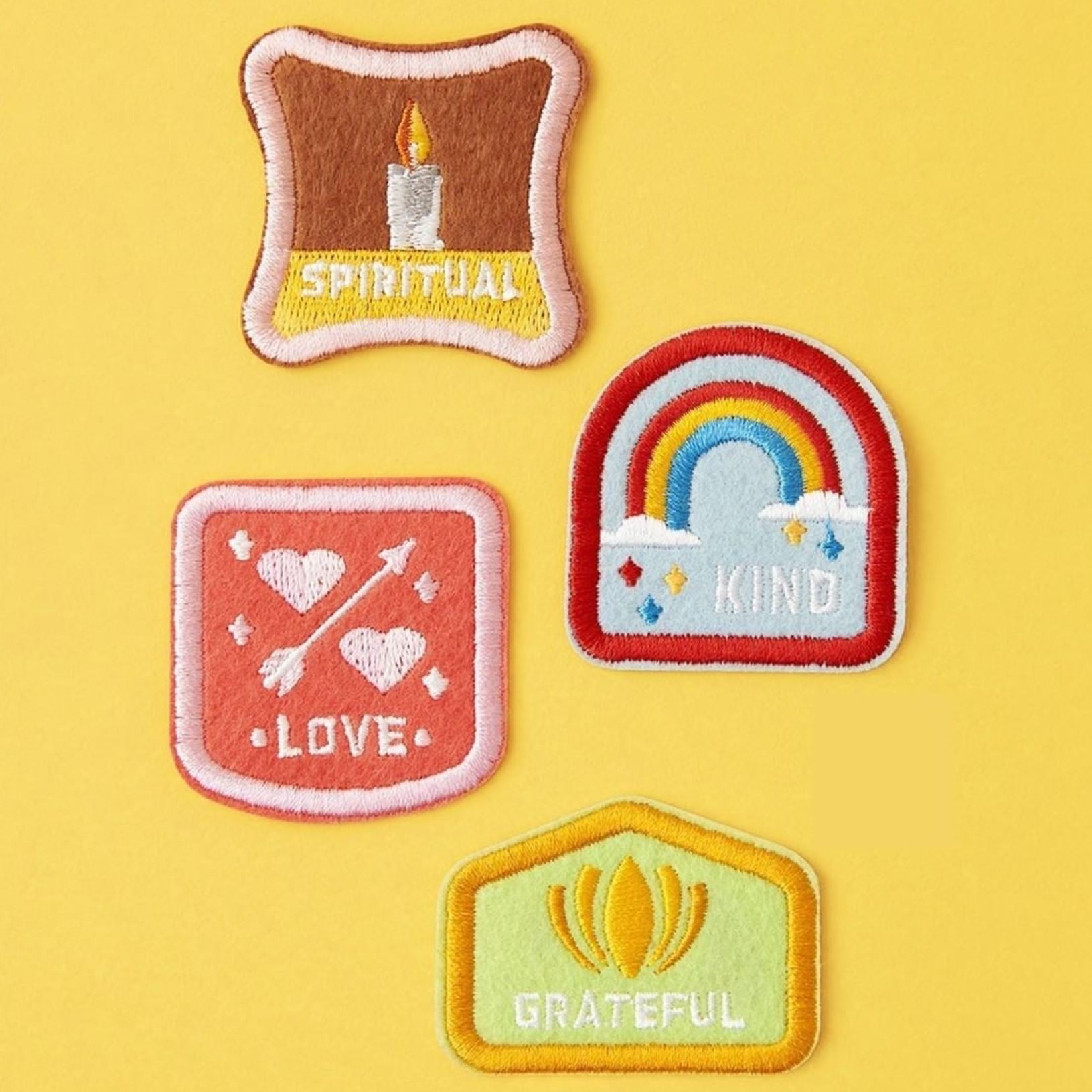 Set of 4 children's character badge patches featuring the traits Kind, Spiritual, Love, and Grateful, with adhesive and iron-on backing, shown on an aqua duffle bag, perfect for customizing backpacks and clothing, set against a yellow backdrop.
