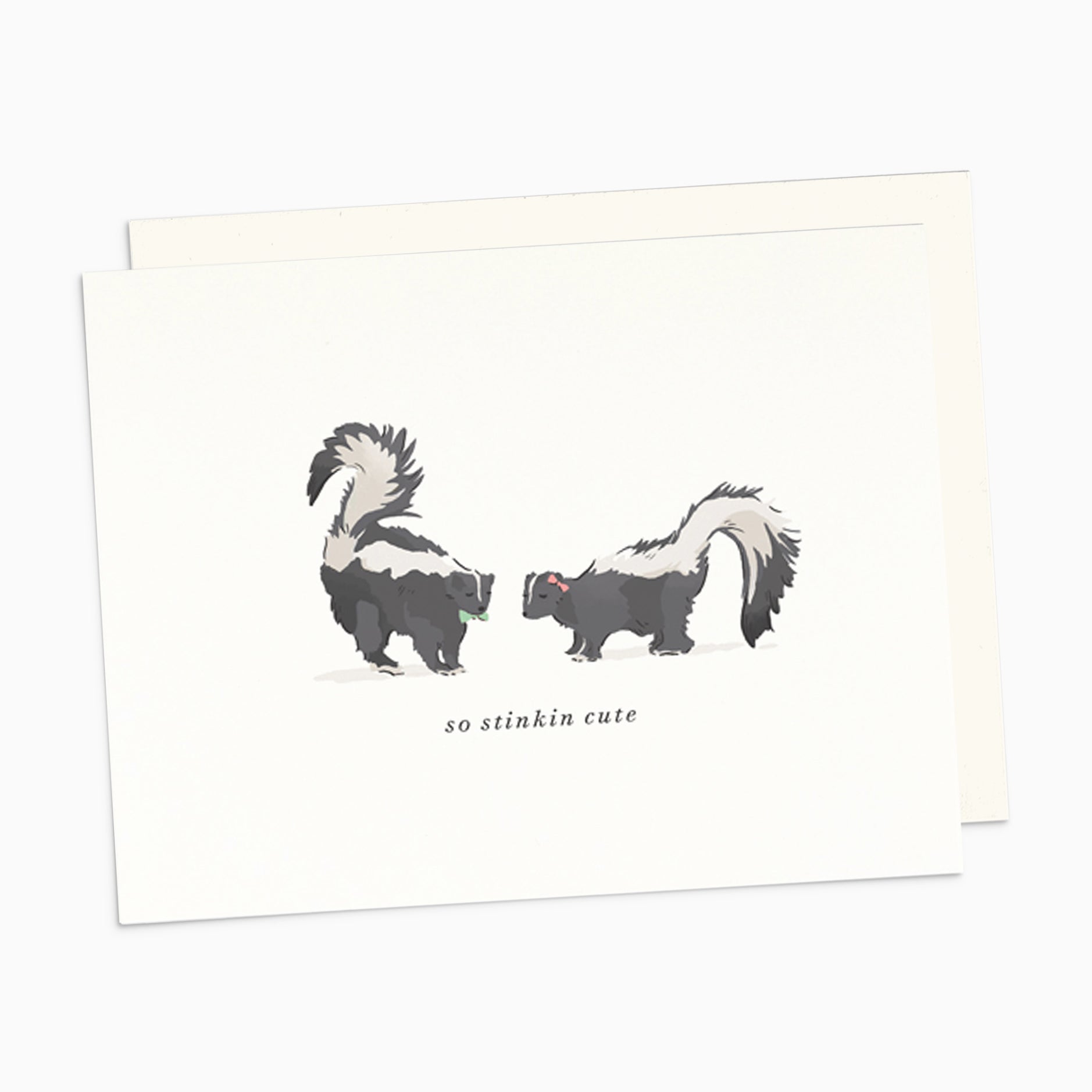 Illustrated New Baby card featuring two adorable skunks facing each other, with the playful words 'So Stinkin' Cute' on warm white cardstock.