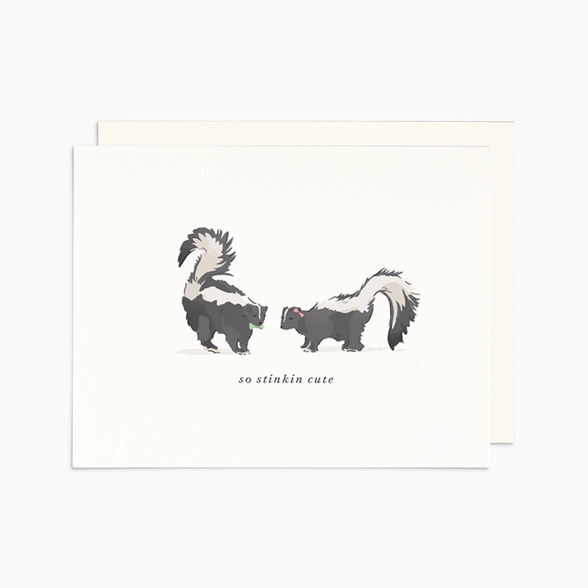 Illustrated New Baby card featuring two adorable skunks facing each other, with the playful words 'So Stinkin' Cute' on warm white cardstock.