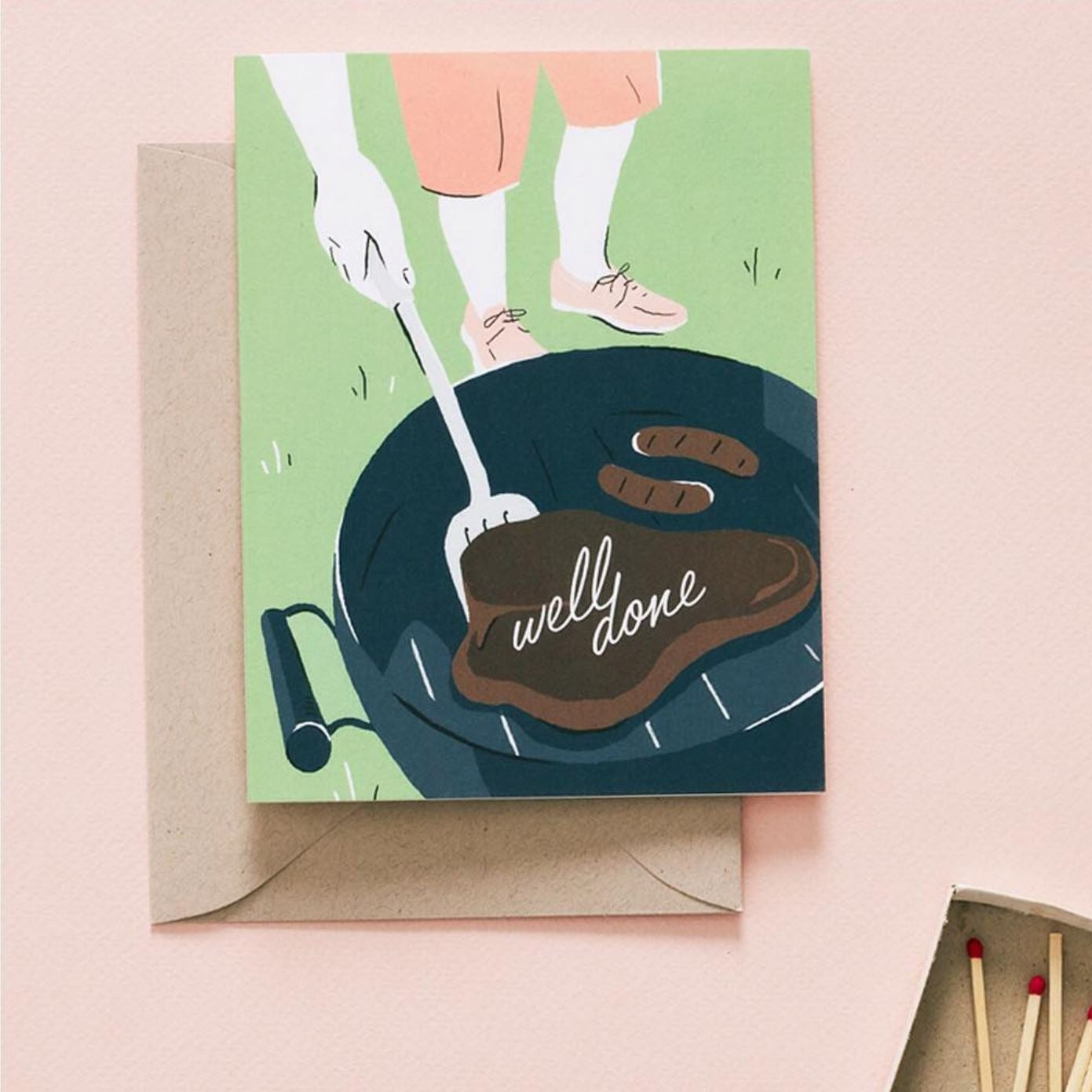 Illustrated 'Well Done' BBQ greeting card on a neutral background, featuring a whimsical steak with the words 'Well Done' written on it, sizzling on a grill.